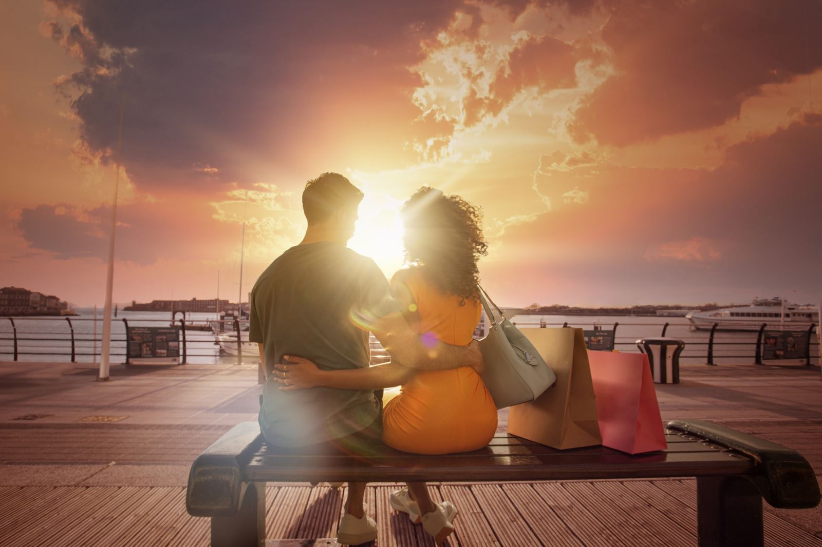 Two people sat on a bench at Gunwharf Quays looking at the sunset